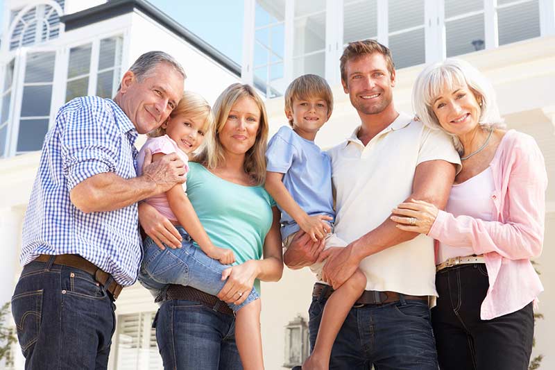 Three generations of a family standing in front of their home.