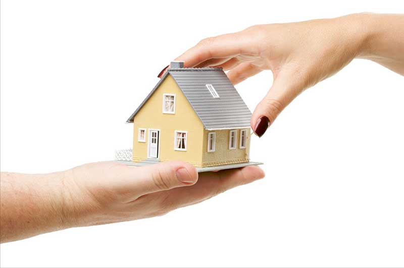 Hands holding a small model house.