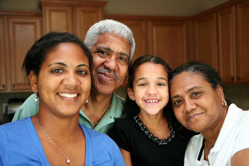 A three-generation family smiling together at home.